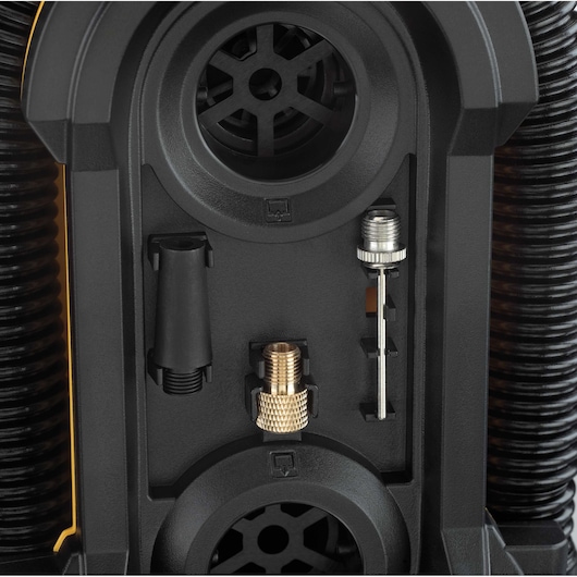 Close-up view of a DEWALT DCC020IB air inflator, showing its accessory storage compartment with various nozzle attachments and connectors organized inside.