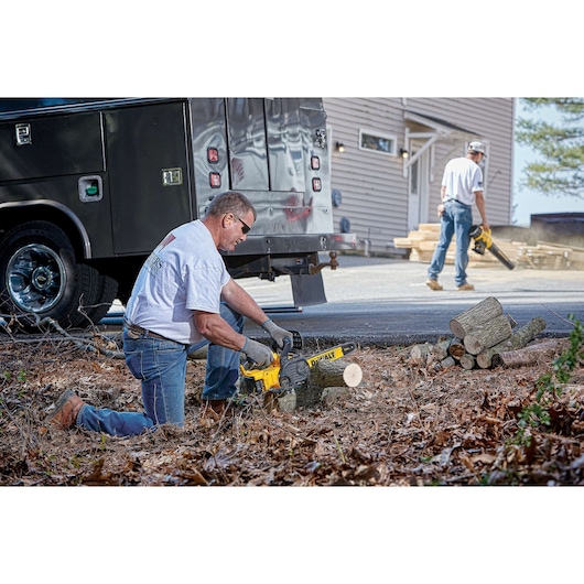 XR® Compact 12 inch Cordless Chainsaw being used by a person to cut wooden logs at work site