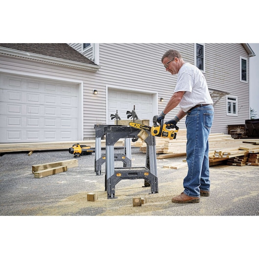 20 volt max x r compact 12 inch cordless chainsaw being used to cut a wooden plank by a person.