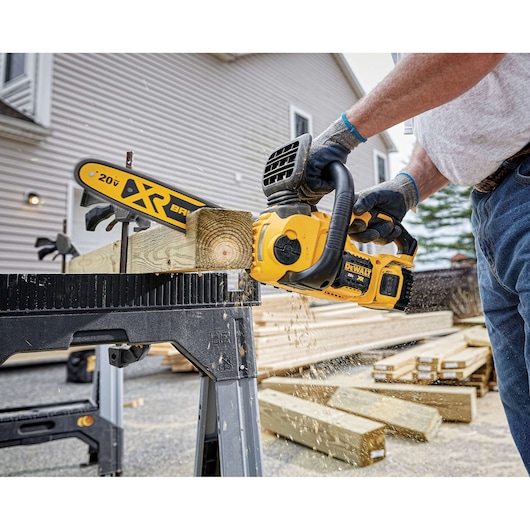 20 volt max x r compact 12 inch cordless chainsaw being used to saw a flat cube of wood.