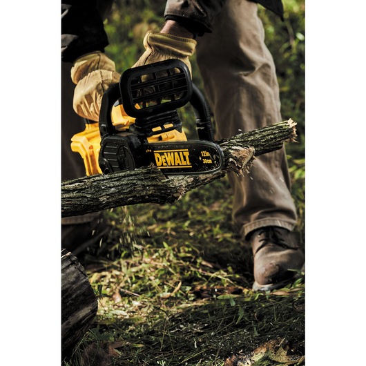 20 volt max x r compact 12 inch cordless chainsaw being used to saw a branch.