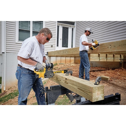 XR® Compact 12 inch Cordless Chainsaw being used by a person to slice through a square wooden log outdoors