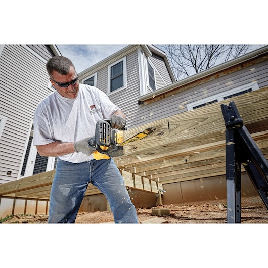 XR® Compact 12 inch Cordless Chainsaw being used by a person to cut through a square log of wood at a worksite