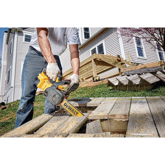 XR® Compact 12 inch Cordless Chainsaw being used by a person to cut through wooden planks outdoors