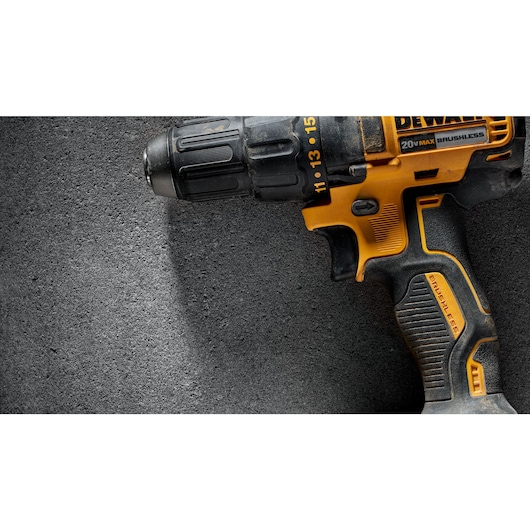 Close-up of a DEWALT cordless power drill with a black and yellow design placed on a textured gray surface.