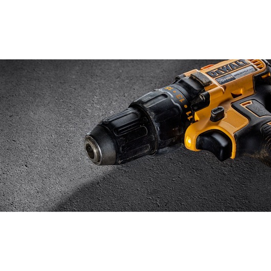 Close-up image of a DEWALT cordless electric drill lying on a textured gray surface.
