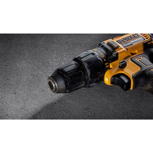 Close-up view of a DEWALT cordless power drill with a black and yellow casing, placed on a textured gray surface.