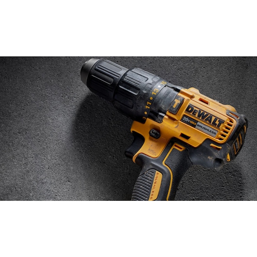 Close-up of a DEWALT 20V MAX brushless cordless drill resting on a dark textured surface.