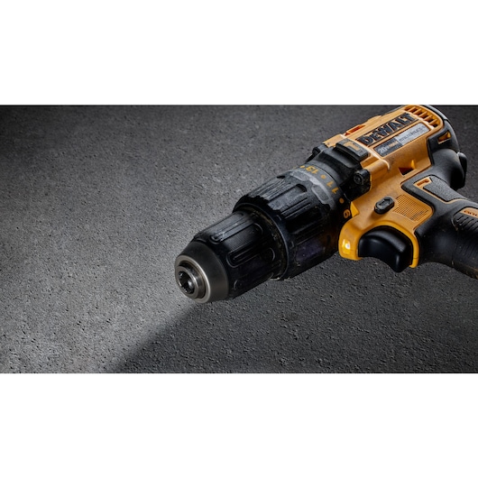 Close-up view of a DEWALT cordless drill with a black and yellow handle on a gray textured surface.