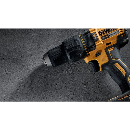 Close-up view of a yellow and black DEWALT 20V cordless brushless drill resting on a dark textured surface.