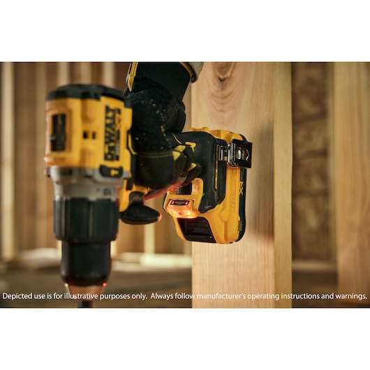 A DEWALT cordless drill, model DCD806D2, being used by a gloved hand to drill into a wooden beam in a construction setting.