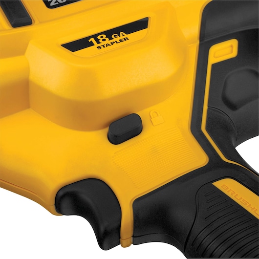 Close-up view of a yellow and black DEWALT 18 GA stapler tool handle with lock icon and textured grip details.