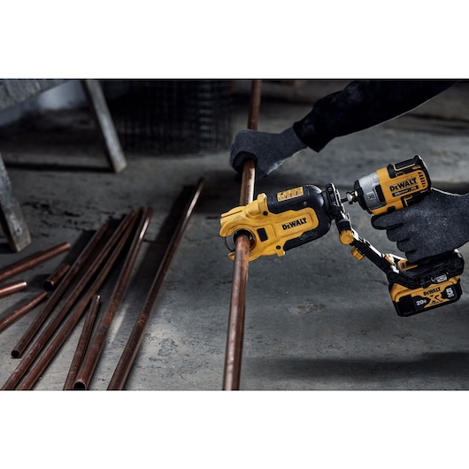 End user using DEWALT IMPACT CONNECT Copper Cutter attachment on Impact Driver to cut copper pipe.