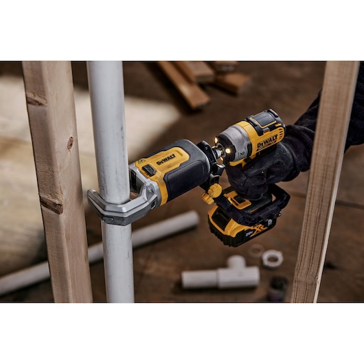 End user using DEWALT IMPACT CONNECT PVC/Pex Cutter attachment on Impact Driver to cut PVC pipe next to wood beam