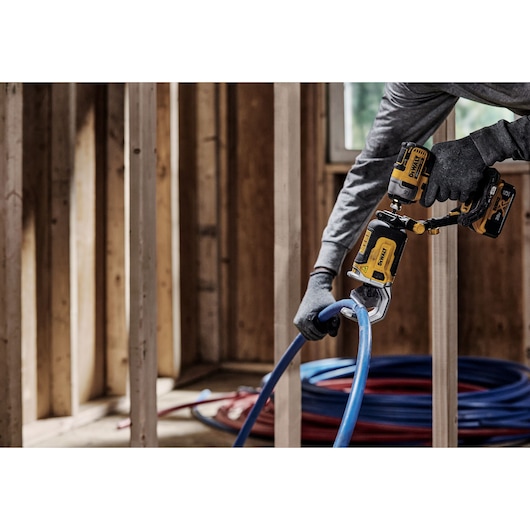 End user using DEWALT IMPACT CONNECT PVC/Pex Cutter attachment on Impact Driver to cut pex tubing near wood framing