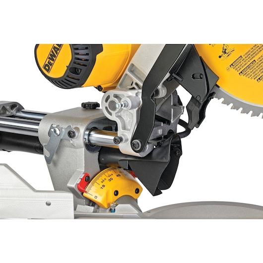 Close-up view of a DEWALT sliding compound miter saw, showing its mechanism, saw blade, angle adjustment scale, and safety guard.