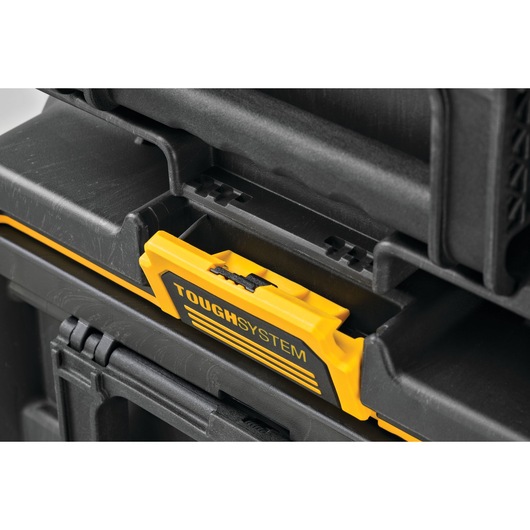 Close-up of a DEWALT ToughSystem locking mechanism on a black and yellow tool storage box. The image shows the interlocking system used to securely stack and connect multiple storage units.