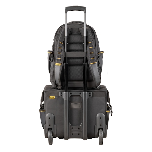 A DEWALT rolling tool bag with telescopic handle, with a black backpack securely attached to the handle. The bag and backpack feature yellow accents and sturdy wheels, pictured from the rear view.