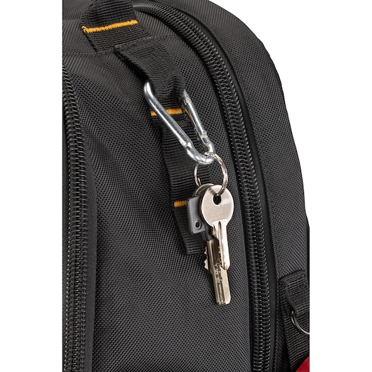 Close-up of a black fabric bag with a metal carabiner attached to a loop, holding a keyring with two metal keys.