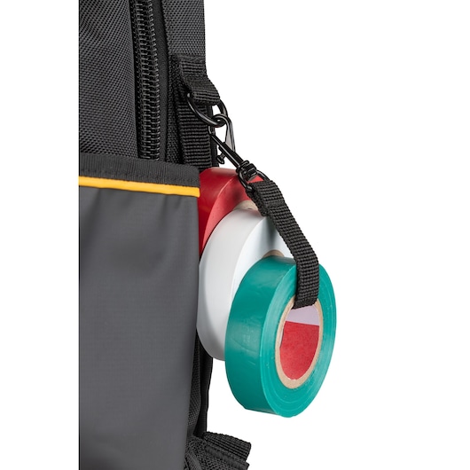 Close-up of rolls of colored adhesive tape attached to a black strap on the side of a black and gray bag with yellow trim.