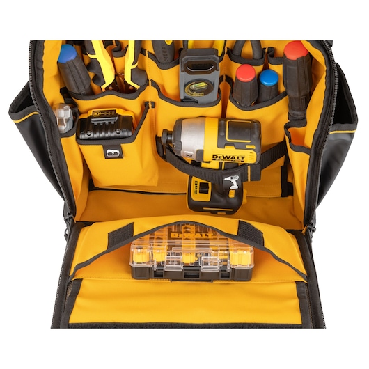 A yellow and black DEWALT tool bag with various hand tools, a cordless power tool, and a plastic organizer inside. The tool bag is open, showing neatly arranged compartments holding screwdrivers, pliers, a level, and a DEWALT impact driver.