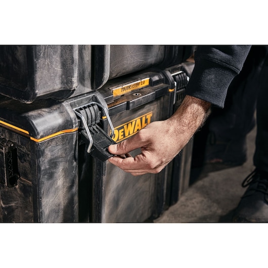 A close-up of a person opening the latch on a DEWALT ToughSystem 2.0 tool storage box.