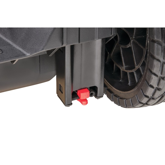 Close-up view of a DEWALT toolbox wheel with a black housing and a small red latch mechanism near the bottom.